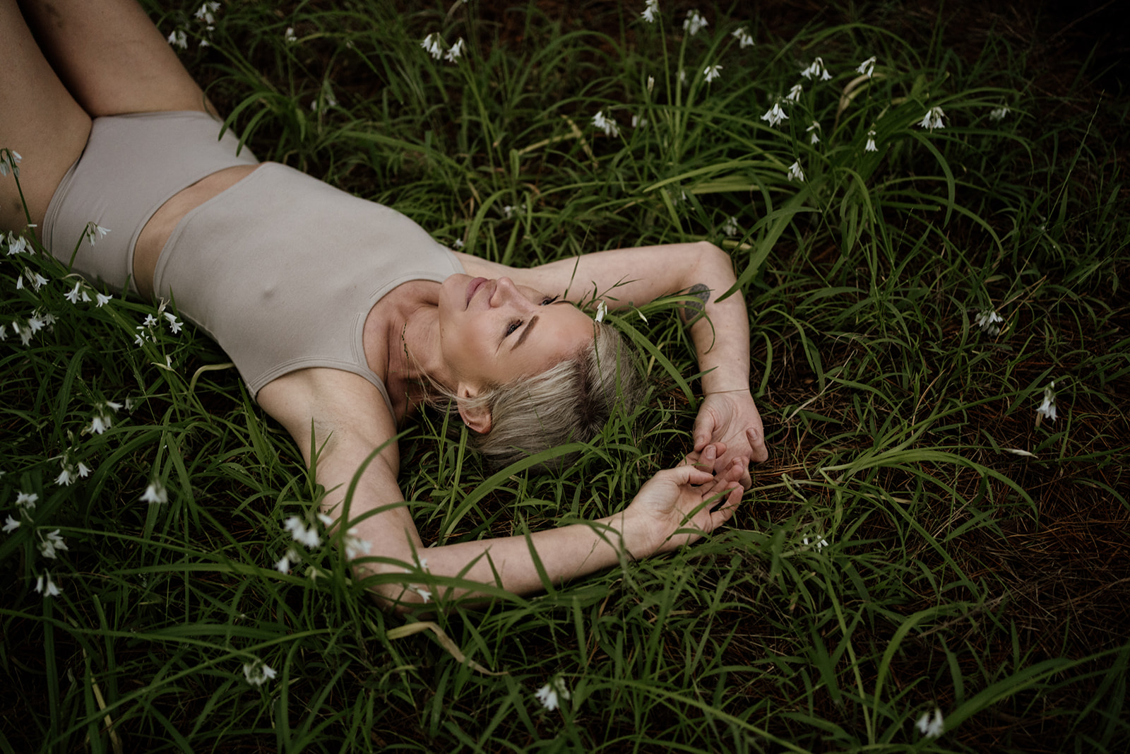 a blonde woman lying in the long grass natural beauty green